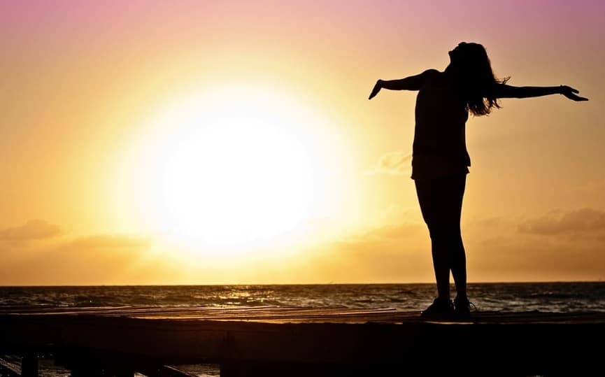 Une femme devant un coucher de soleil à la plage