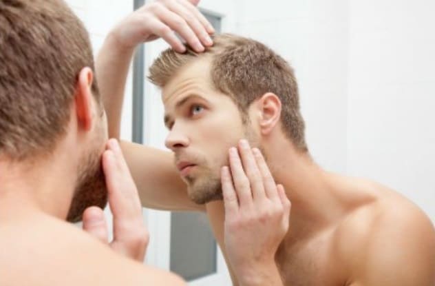 Homme examinant ses cheveux dans un miroir