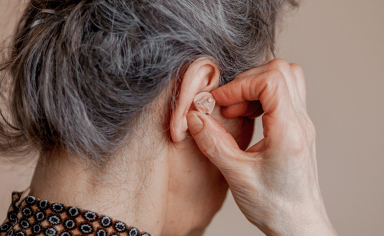 personne âgée cheveux gris met prothèse auditive oreille