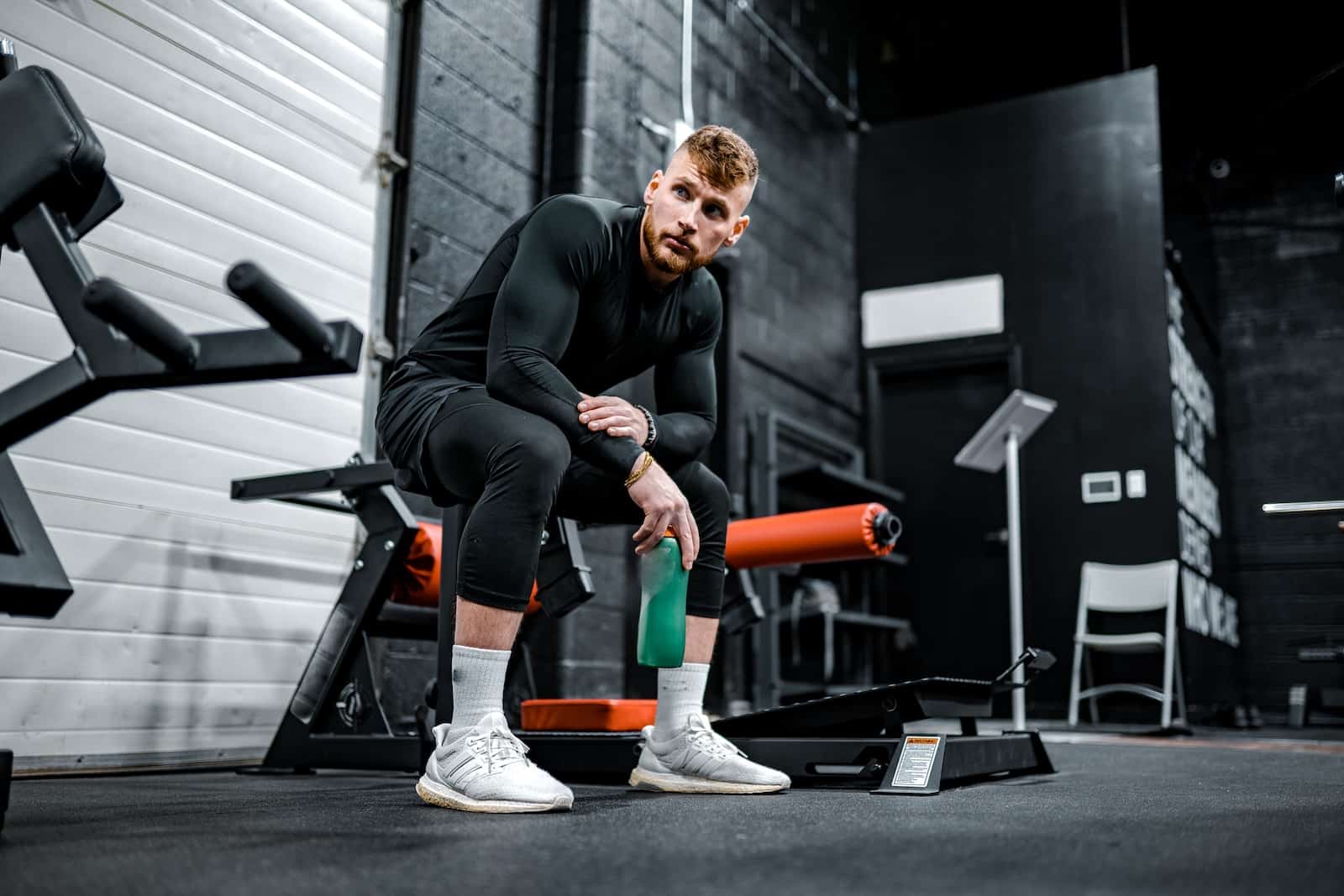 chemise à manches longues noire et pantalon noir assis sur l'équipement d'exercice